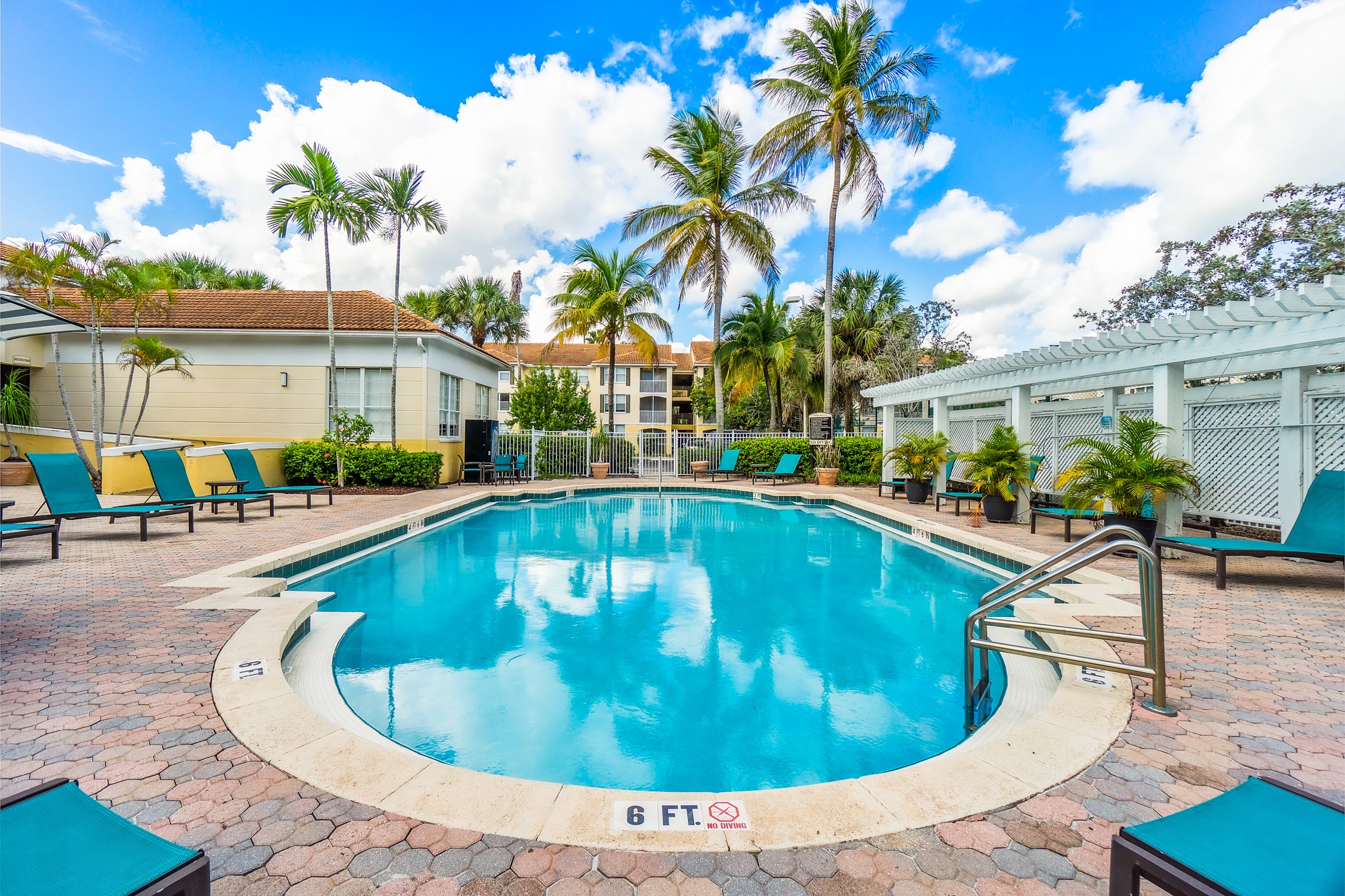 A swimming pool surrounded by palm trees and lounge chairs.